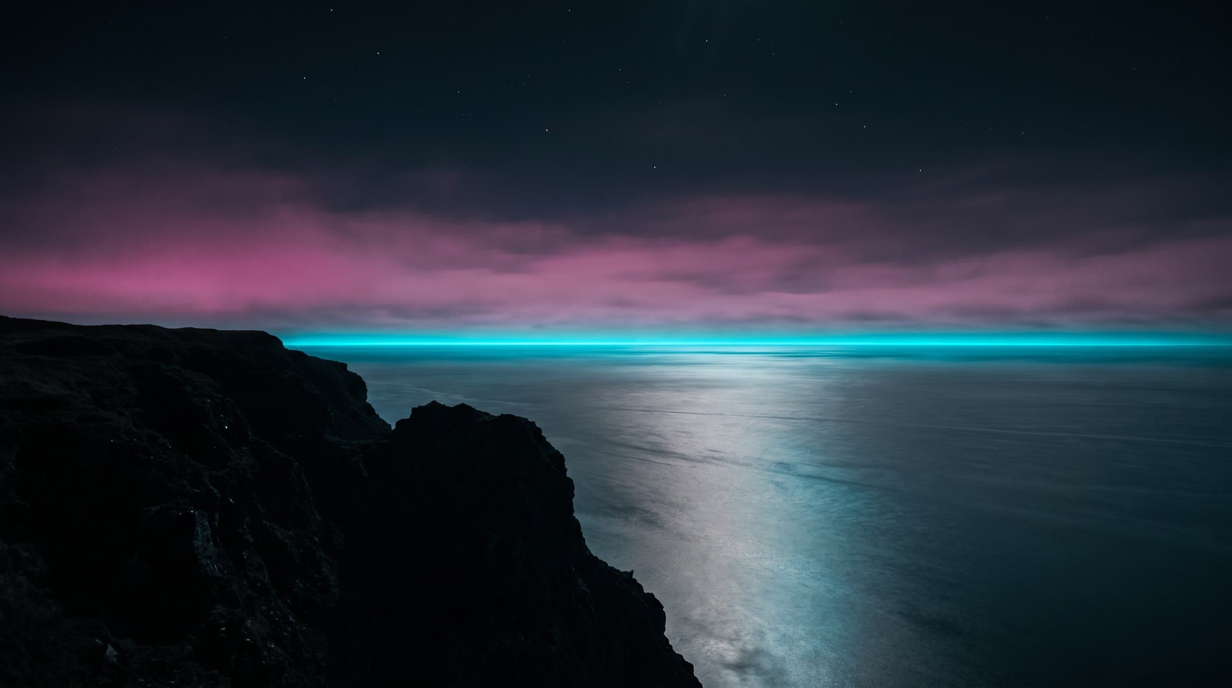 Night sea from a cliff, a cyan line on the horizon